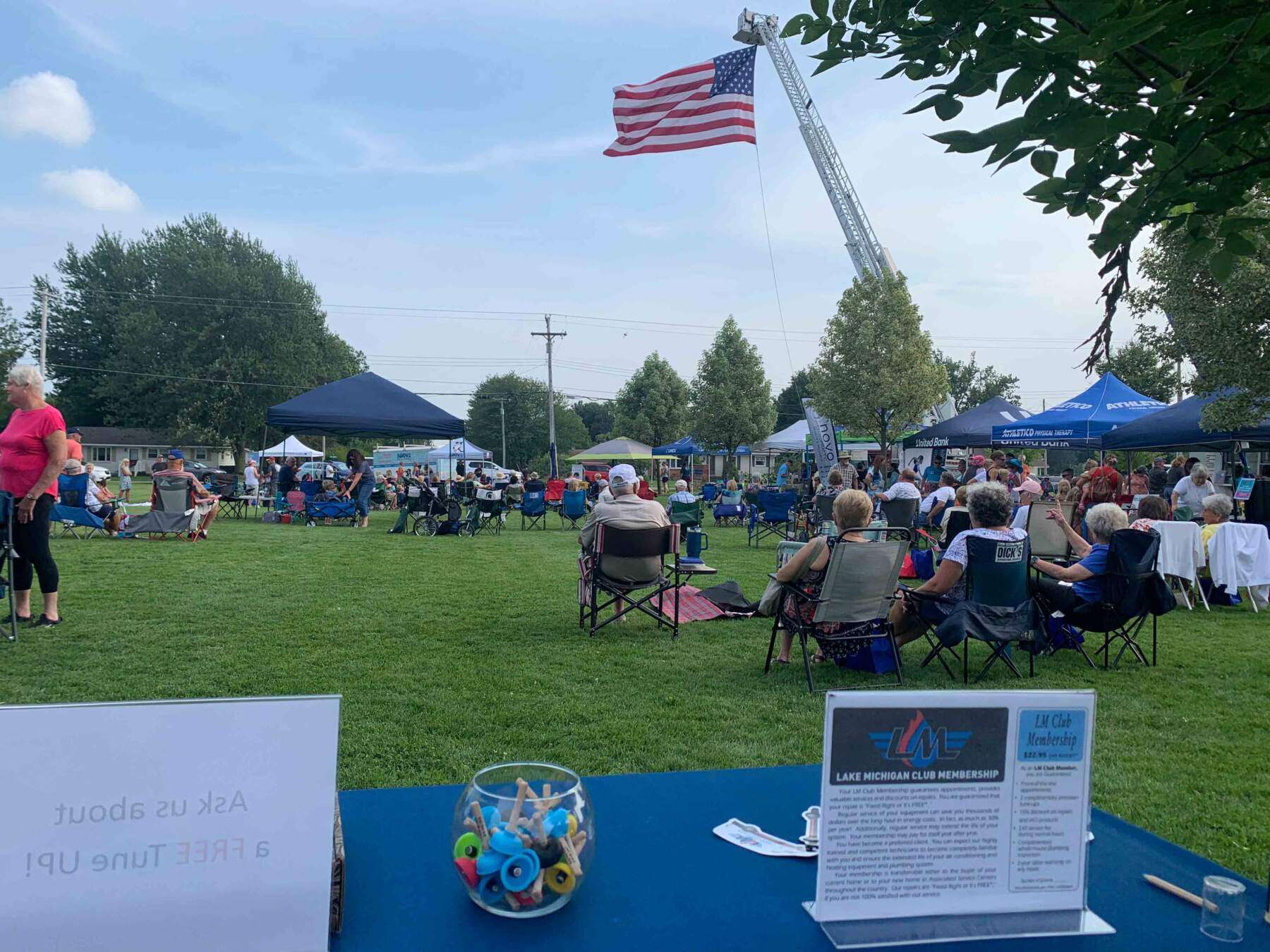 Small crowd seated in folding chairs at a summer outdoor event.